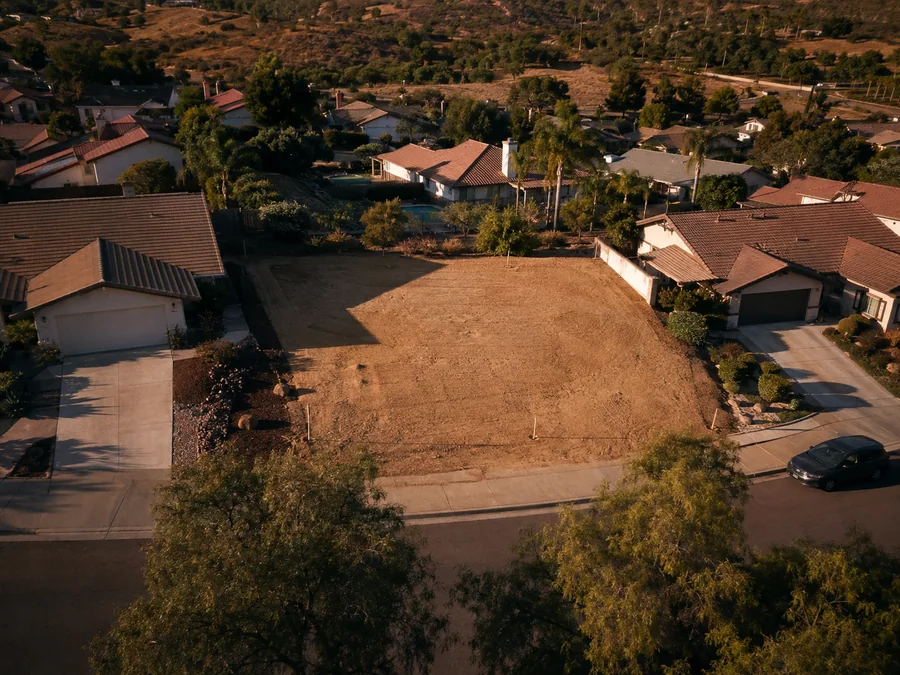 Lote vacío visto desde el aire, entre casas terminadas